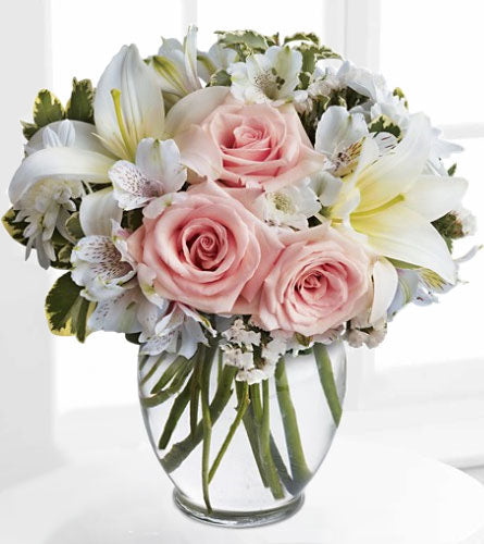 Divine Style - arrangement of pink roses and white lilies in a clear vase.