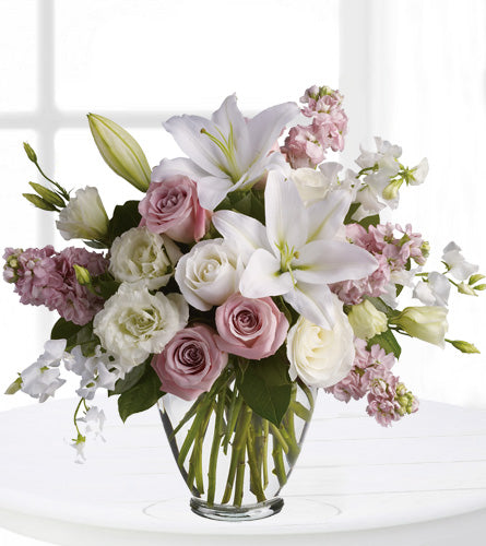 Isn't it Beautiful by Teleflora - arrangement of white and mauve flowers in a clear glass vase.