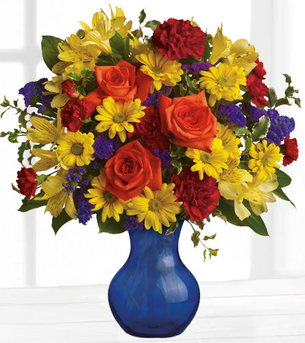 Teleflora's Three Cheers For You! - colourful bouquet of flowers in a blue glass vase.