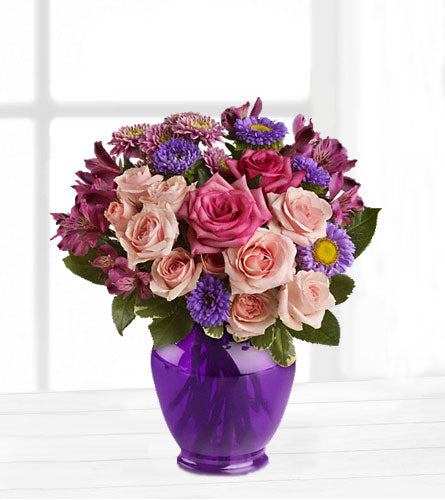 Purple Medley Bouquet - pink roses and purple mixed flowers in a purple glass vase.