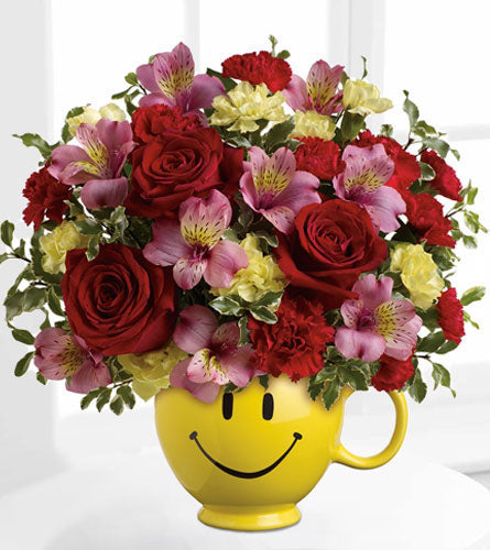 So Happy You're Mine Bouquet - colourful arrangement of mixed flowers in a yellow smiley face mug.