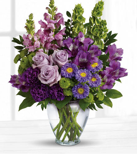 Lavender Charm Bouquet - floral arrangement of purple, green and lavender flowers with in a clear glass vase.