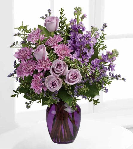 Together at Twilight Bouquet - floral design of mixed purple and lavender flowers with greenery in a purple glass vase.
