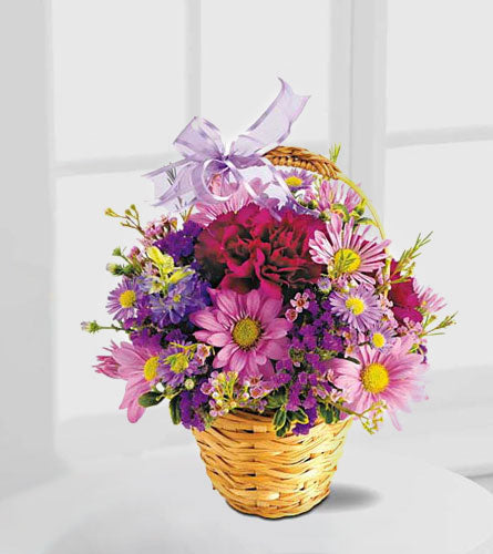 Teleflora's Lavender Garden - woven basket of colourful flowers with a purple bow.