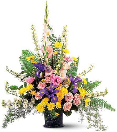 Loving Tribute - colourful flower arrangement with roses, daisies, carns and ferns in a black vase.