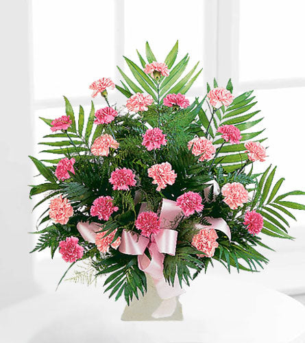 Classic Carnation Arrangement - bouquet of pink carnations with green leaves in a white container.