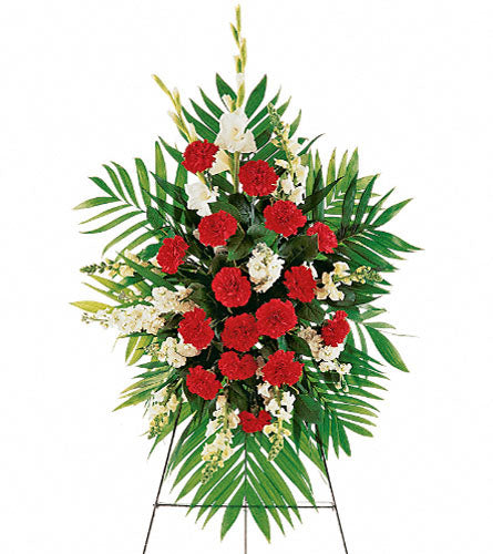 Cherished Moments Spray - Floral arrangement with red carnations, white flowers, and green leaves on a stand.