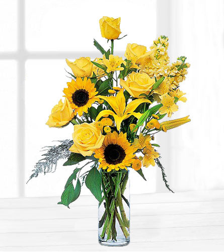 Blazing Sunshine Arrangement - Bouquet of yellow flowers including sunflowers and roses in a clear vase.
