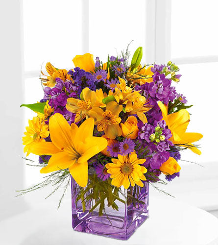 Morning Sunrise Bouquet - mix of yellow and lavender flowers in a clear, glass cube vase.
