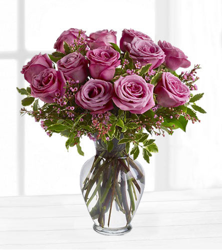 Dozen Lavender Roses - Bouquet of 12  lavender roses with pink wax flowers in a clear vase.