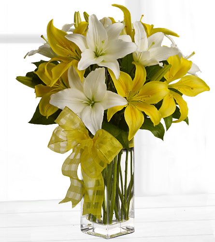 Fresh & Bright Lily Bouquet - arrangement of yellow and white lilies in a clear rectangular vase with a decorative yellow bow.