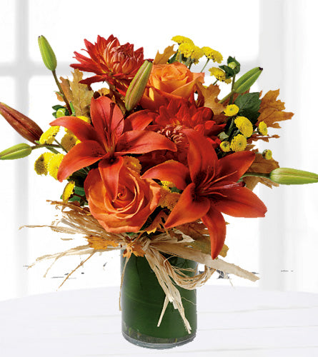 Orange Zest - orange and yellow flowers in a leaf wrapped vase and raffia bow.