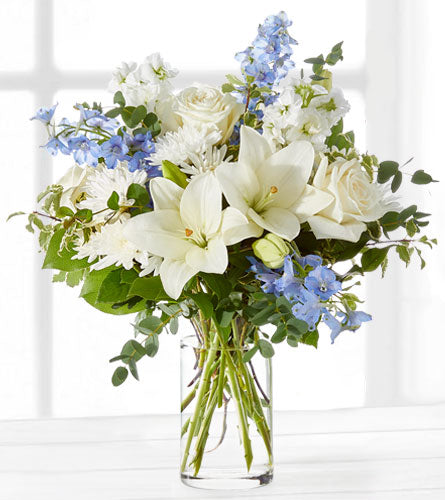 Peace and Light - bouquet of white lilies and blue flowers in a clear vase.