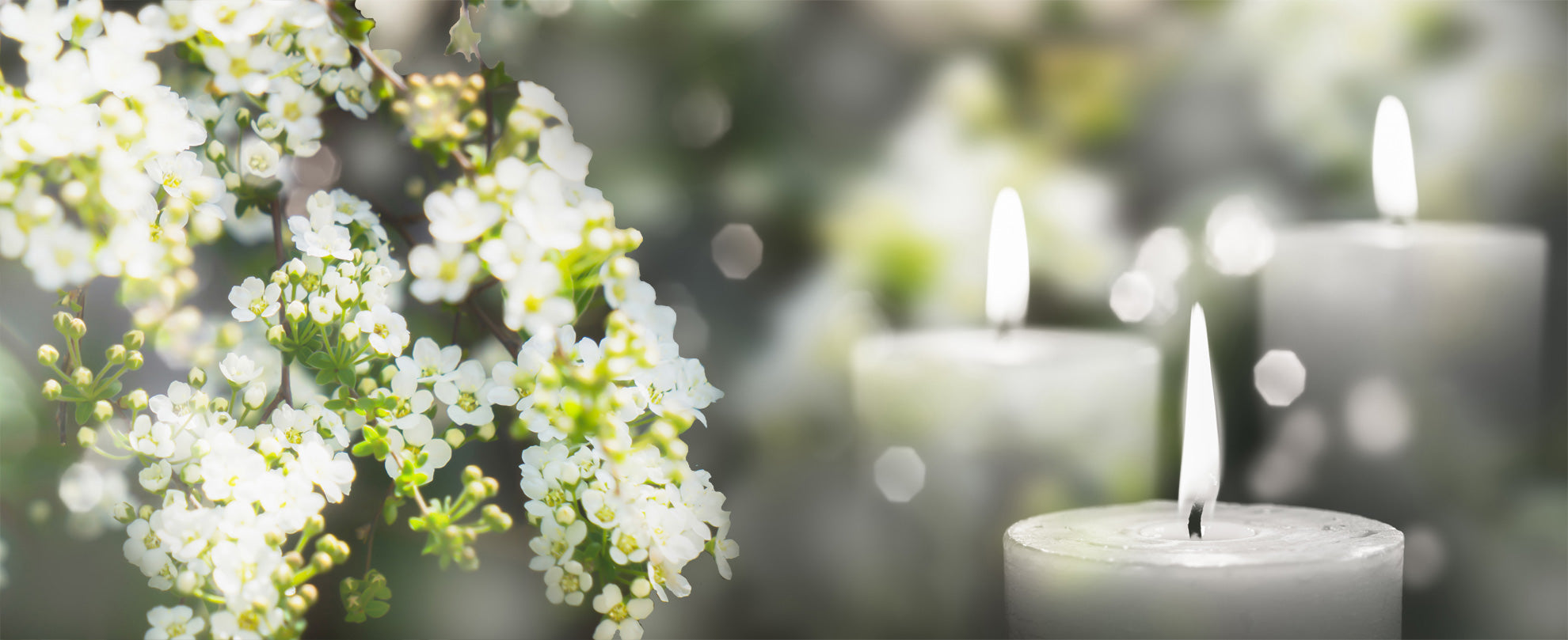 White sympathy flowers with a group of white pillar candles.